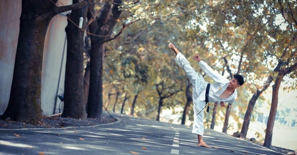 Karate student performing high kick outdoors for beginner martial arts practice