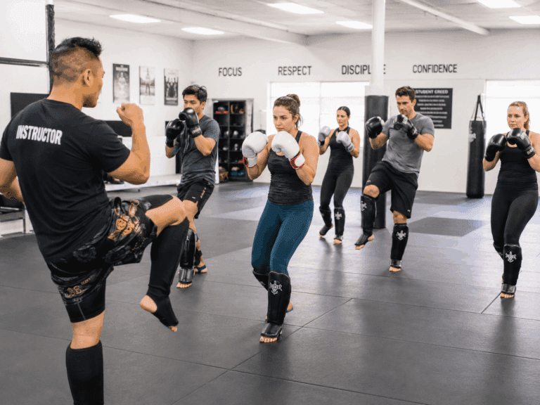 Instructor leads controlled knee drill during beginner kickboxing workout