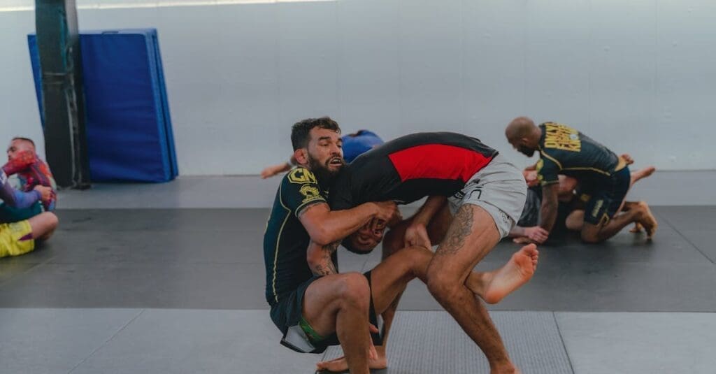 Two athletes training on the mat, showcasing dynamic movement as one attempts a takedown—a fundamental aspect of how basic BJJ positions explained in class are transitionally applied in No-Gi Jiu-Jitsu.